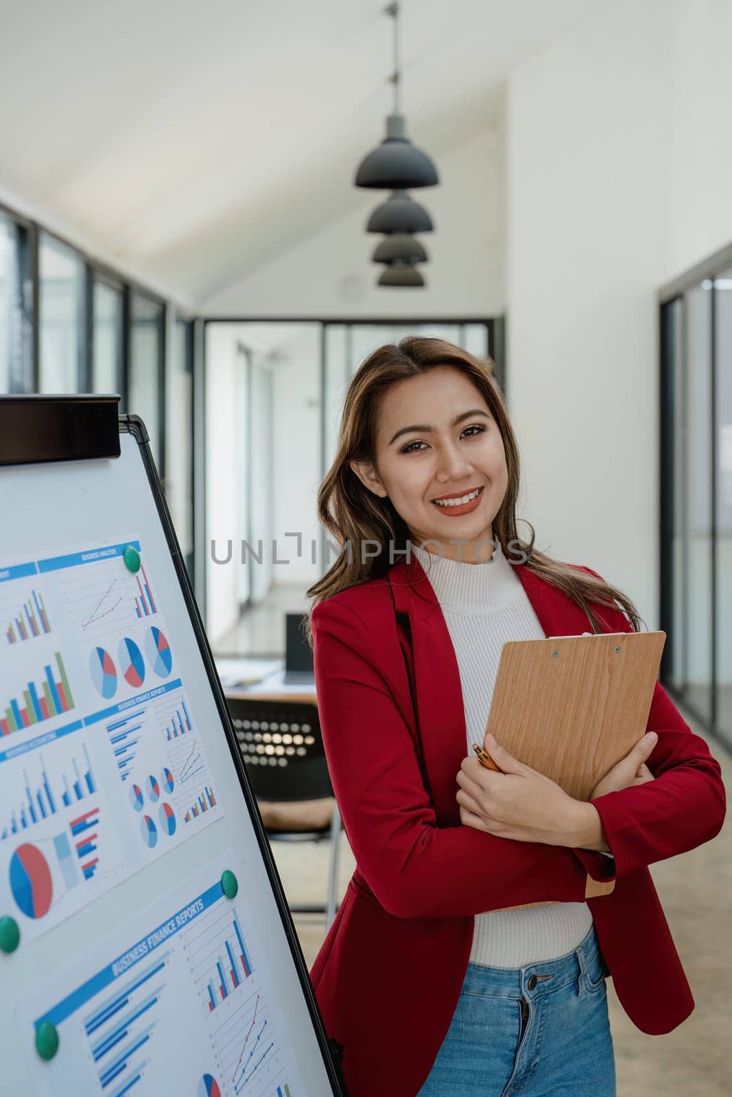 portrait of Beautiful young asian businesswoman presents business profits to colleagues at meeting, explaining business turn over on flipchart to coworkers in office with using tablet by Manastrong