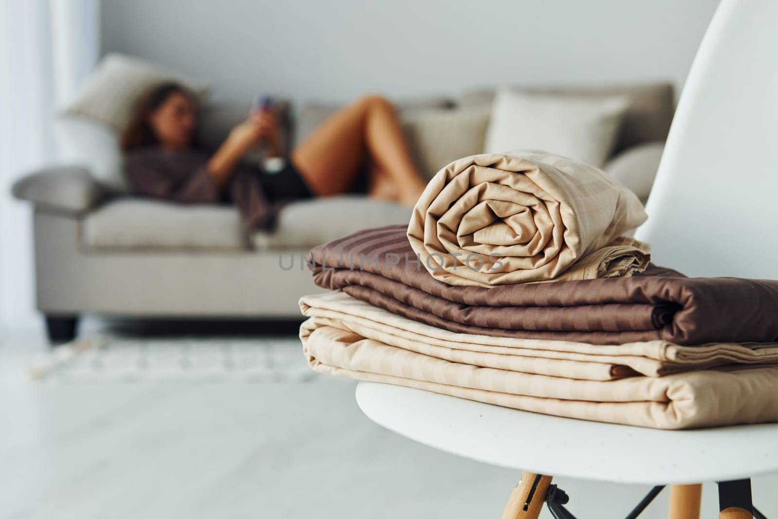 Girl lying down on the bed with smartphone. Interior and design of beautiful modern bedroom at daytime.