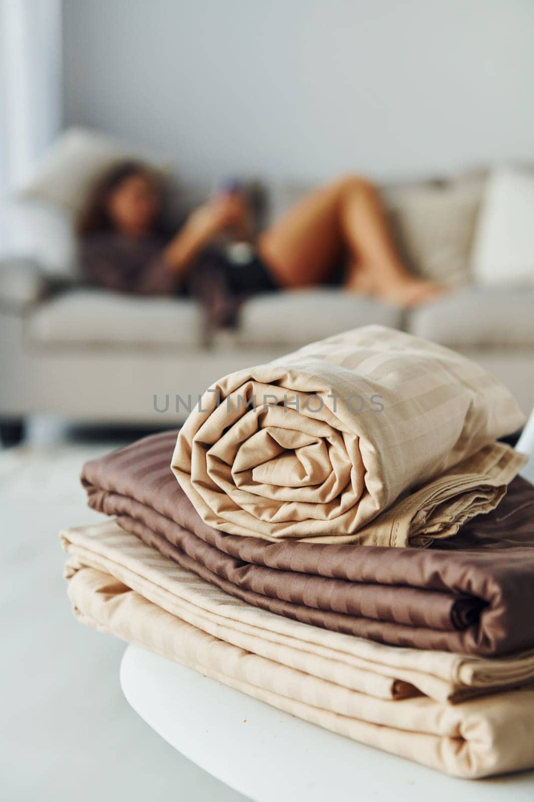 Girl lying down on the bed with smartphone. Interior and design of beautiful modern bedroom at daytime.