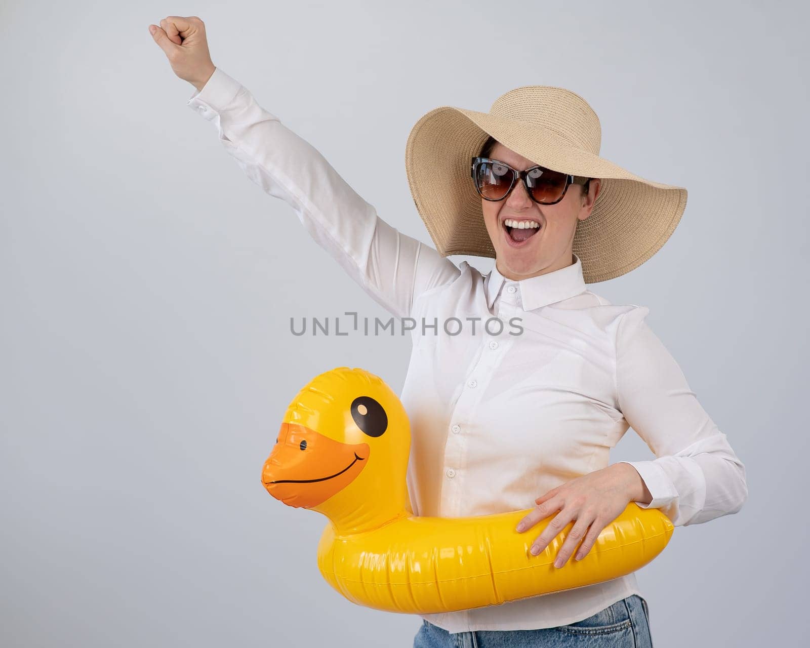 Excited woman dreaming about vacation, wearing sunglasses, hat and inflatable duck