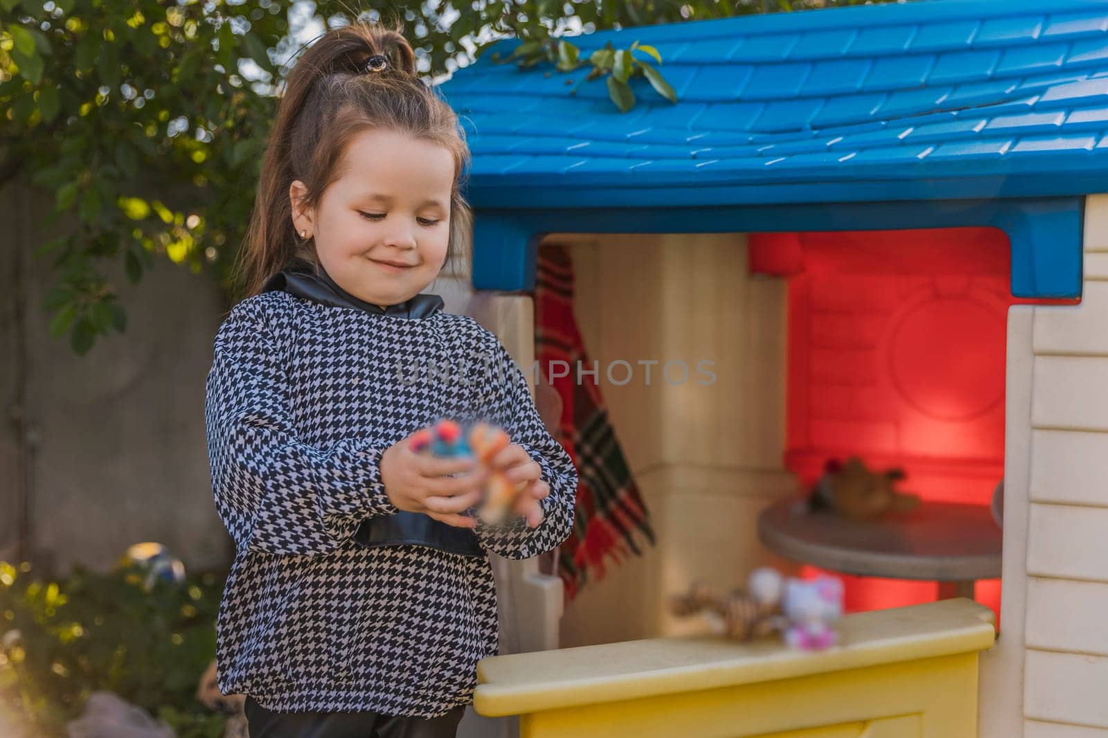 girl is playing in her little house, looking out the door