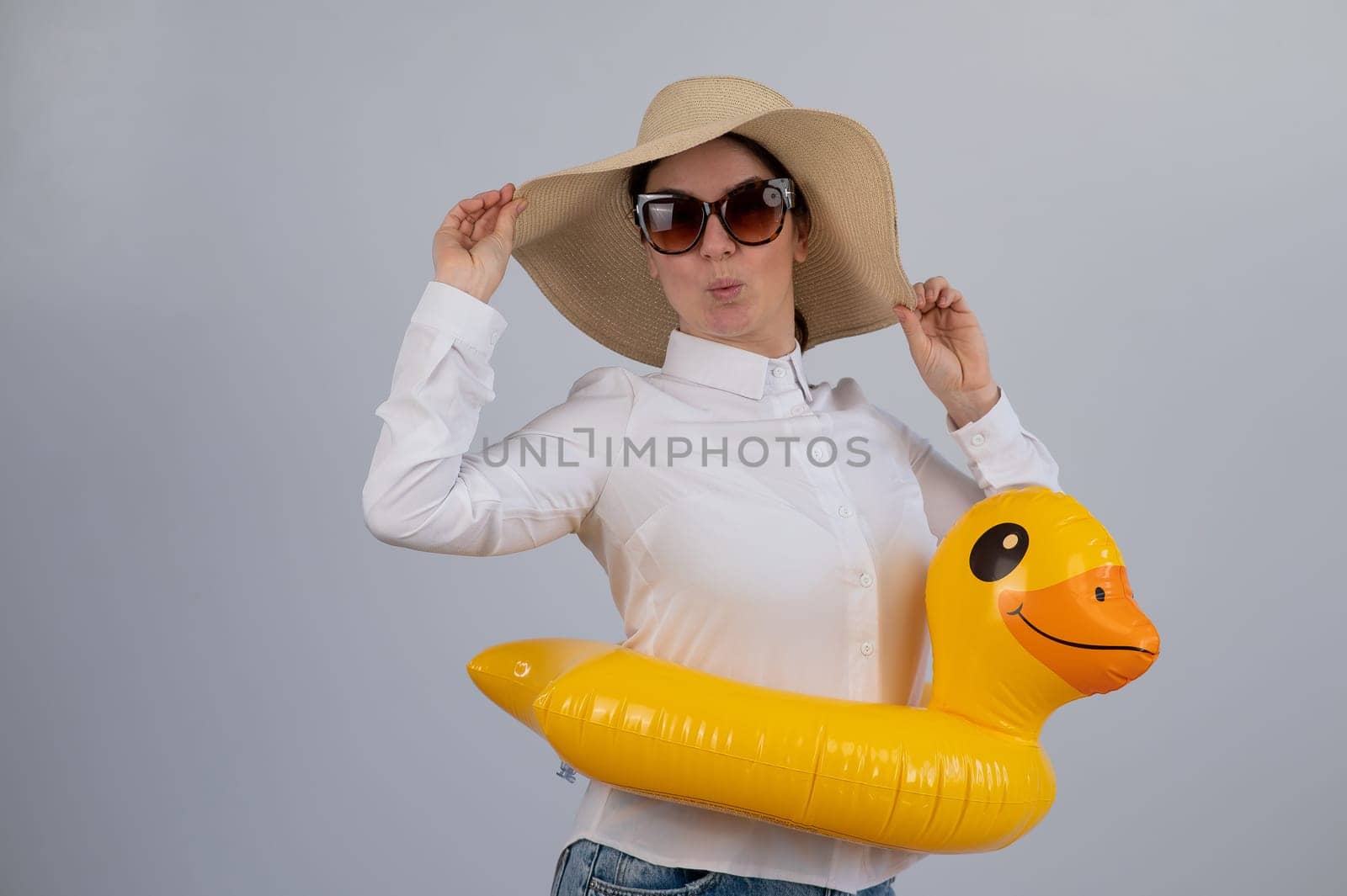 Excited woman dreaming about vacation, wearing sunglasses, hat and inflatable duck