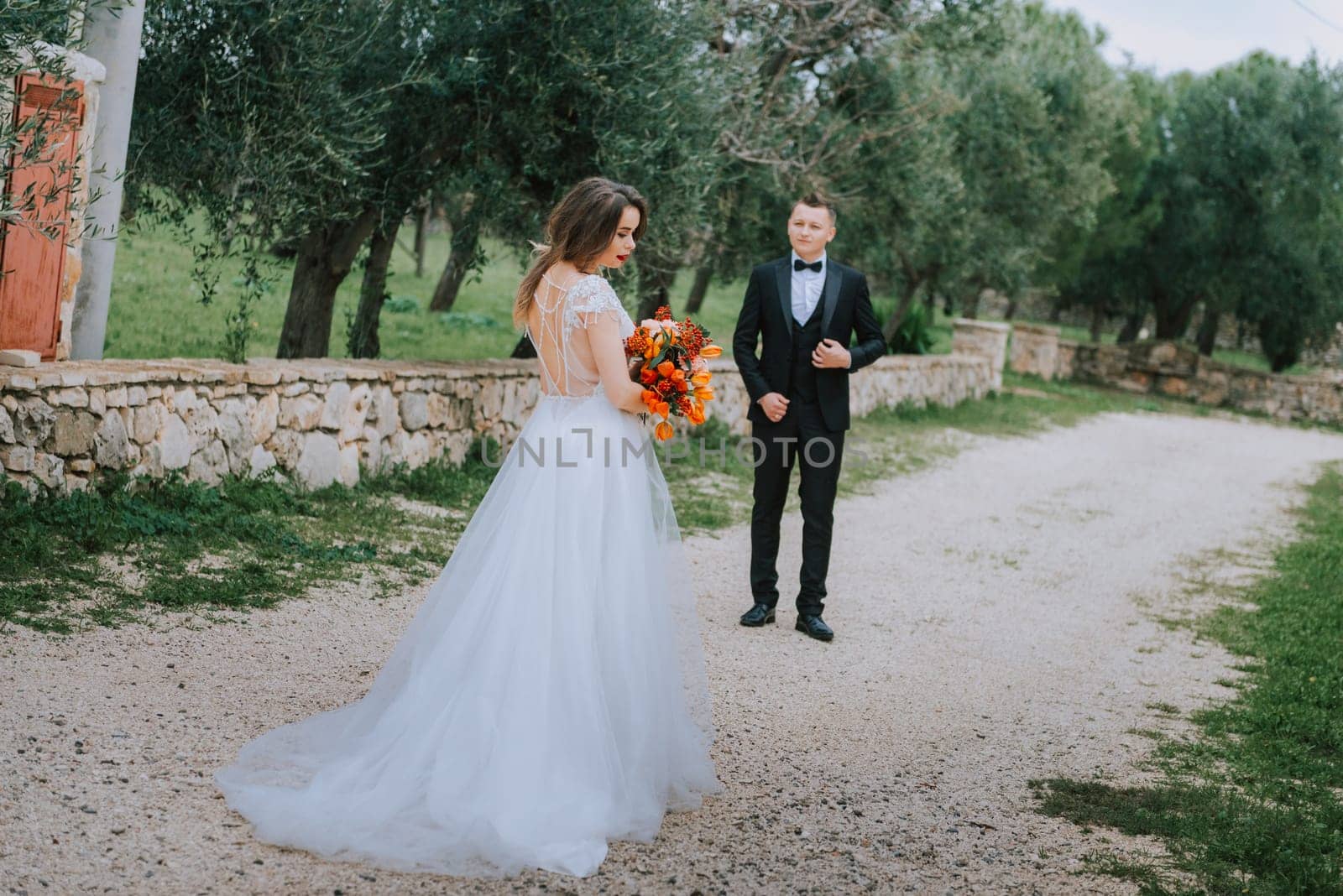 Happy stylish smiling couple walking in Tuscany, Italy on their wedding day. The bride and groom walk down the street by the hands. A stylish young couple walks. Husband and wife communicate nicely. Lovers run through the streets of the city by Andrii_Ko