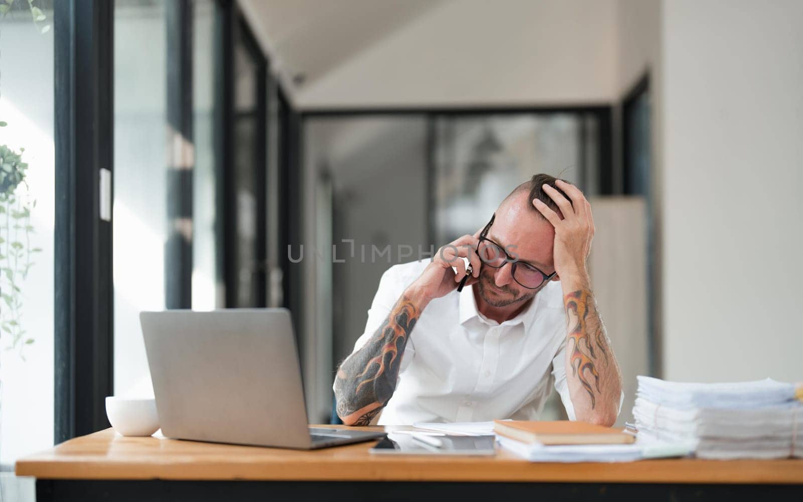 Frustrated stressed business man talking on the phone in office..