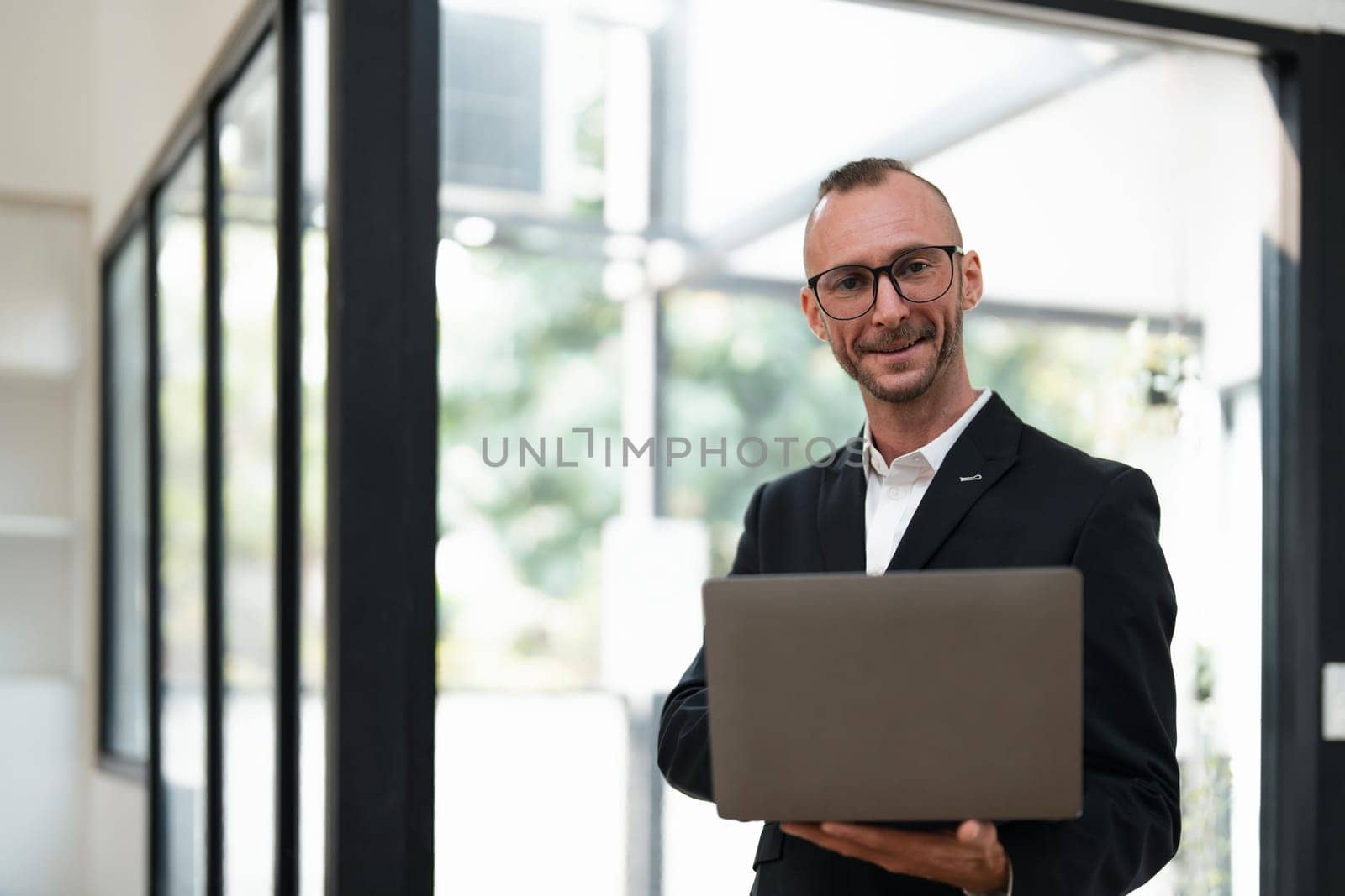 businessman handsome smiling using laptop while standing in office.