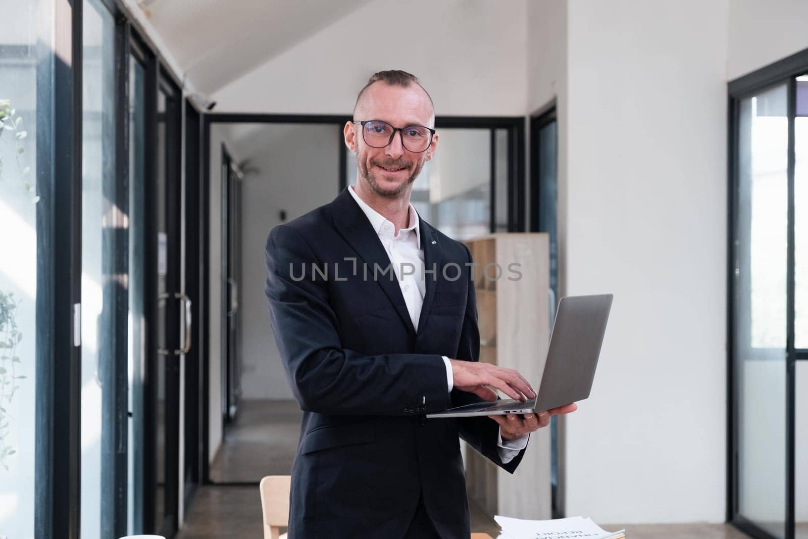 businessman handsome smiling using laptop while standing in office.