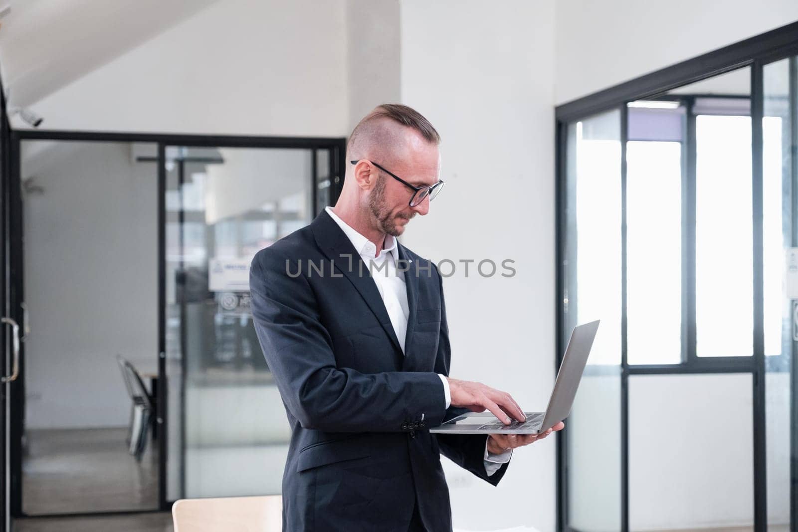 businessman handsome smiling using laptop while standing in office.