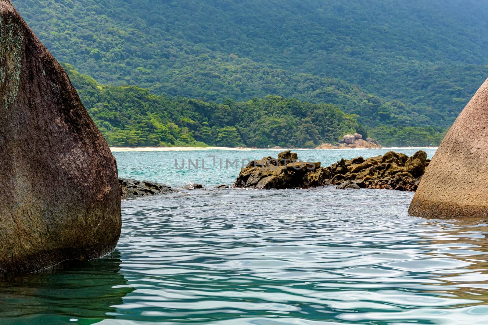 Beach and tropical forest in Trindade, Paraty seen through the rocks