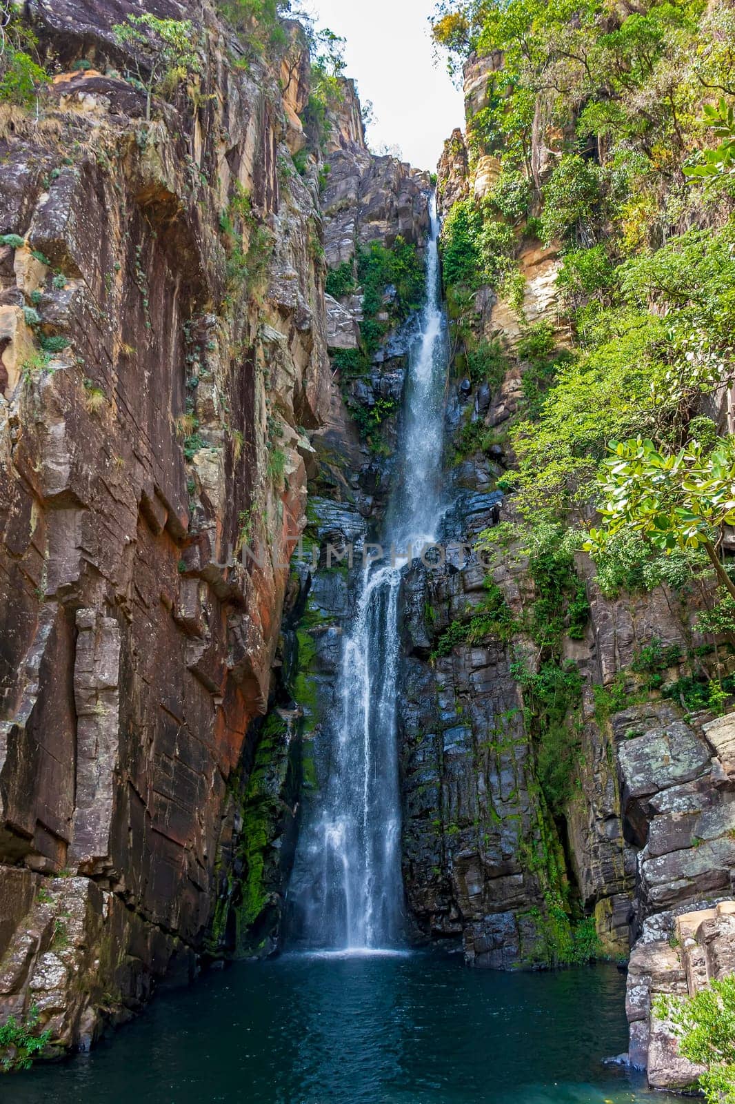 Beautiful waterfall called Veu da Noiva between moss covered rocks and the vegetation of an area with nature preserved in the state of Minas Gerais, Brazil