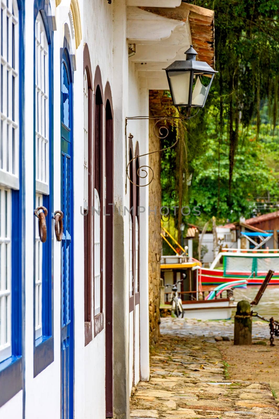 Colonial style house facades with old metal lantern and boats in the background in the historic town of Paraty, Rio de Janeiro, Brazil