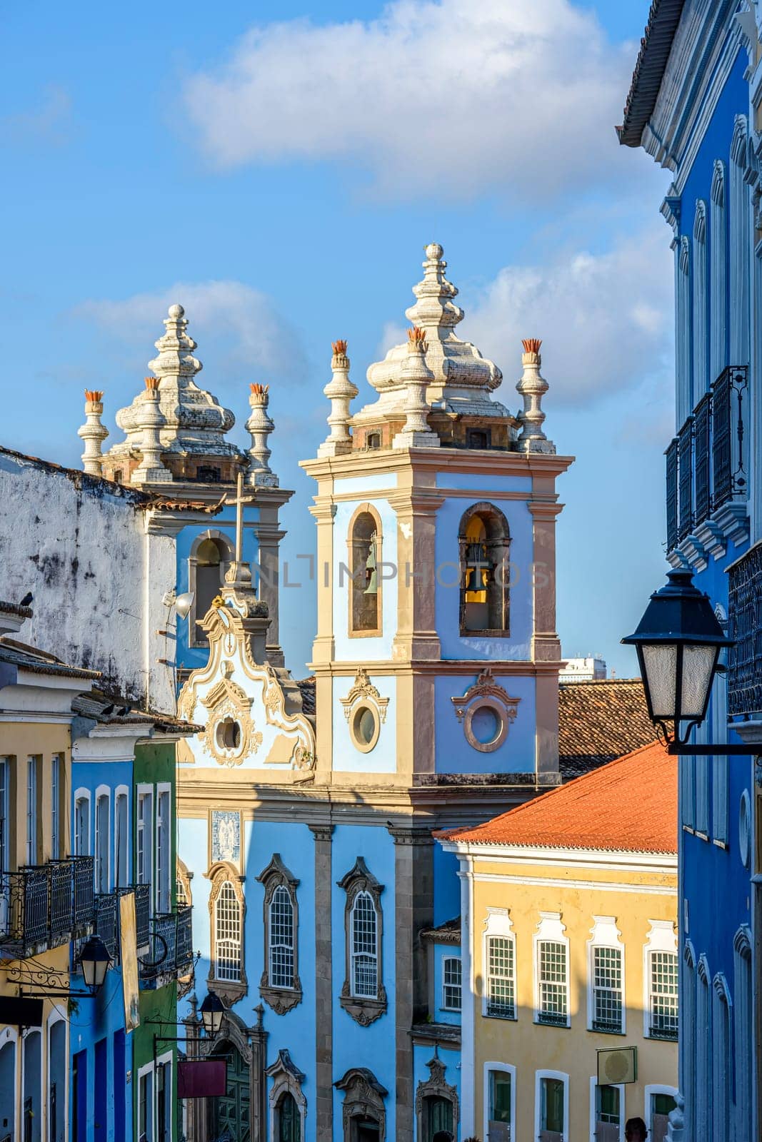 Old facades of colorful colonial-style houses, lanterns and windows and a tower of an old baroque church in Pelourinho, the famous historic center of Salvador, Bahia