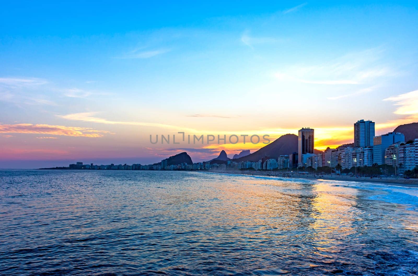 Copacabana beach sunset in Rio de Janeiro with the light coming from behind the buildings and hills