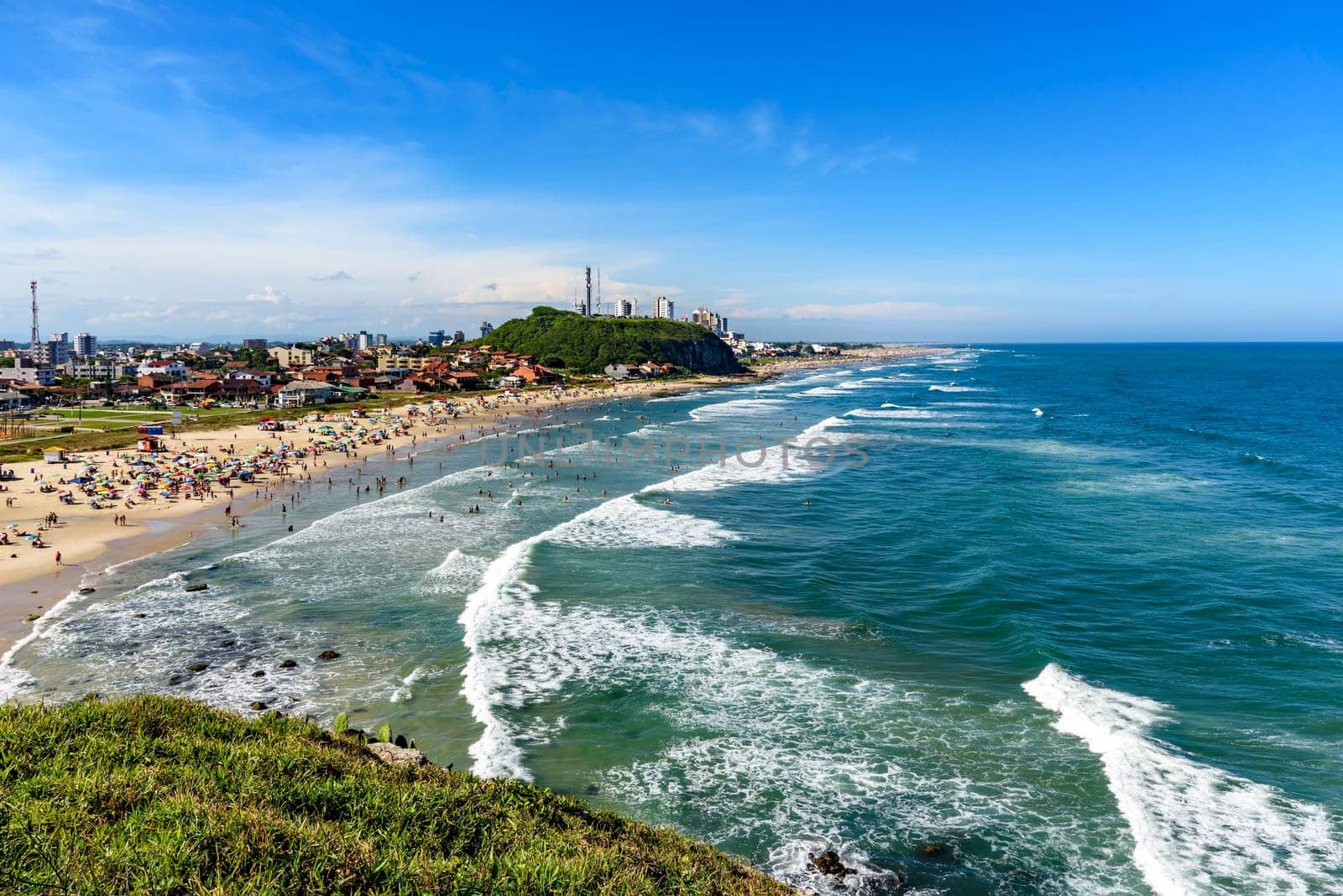Crowded beach and the city on a beautiful sunny day in the summer of Torres city on the coast of Rio Grande do Sul state, Brazil