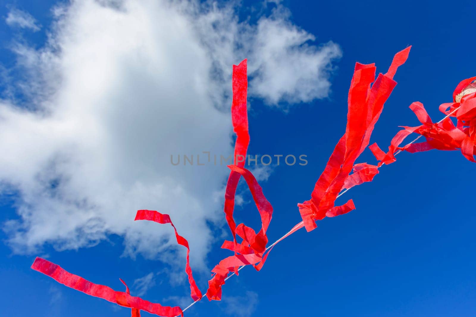 Decorative vivid red ribbons prepared for a religious festival in the city of Lavras Novas in Minas Gerais swaying in the wind with blue sky