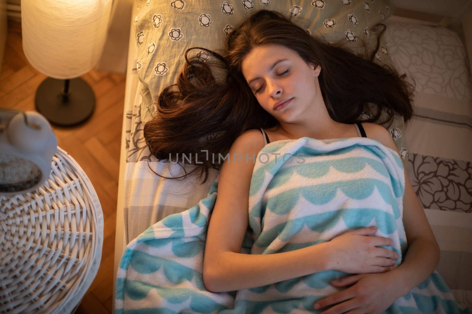 A girl with long hair sleeps peacefully on her bed. A girl under a soft blanket.