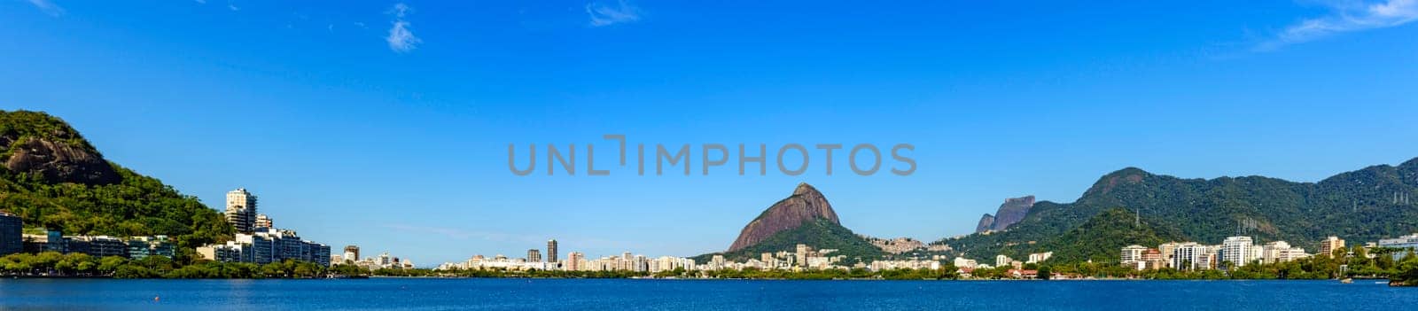 Panoramic image of the famous Rodrigo de Freitas lagoon in Rio de Janeiro surrounded by the city, mountains and greenery on a sunny summer day