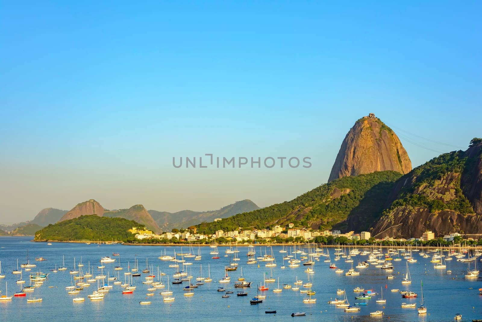 Guanabara Bay with boats floating on the water and the Sugarloaf Mountain in the background during the summer afternoon