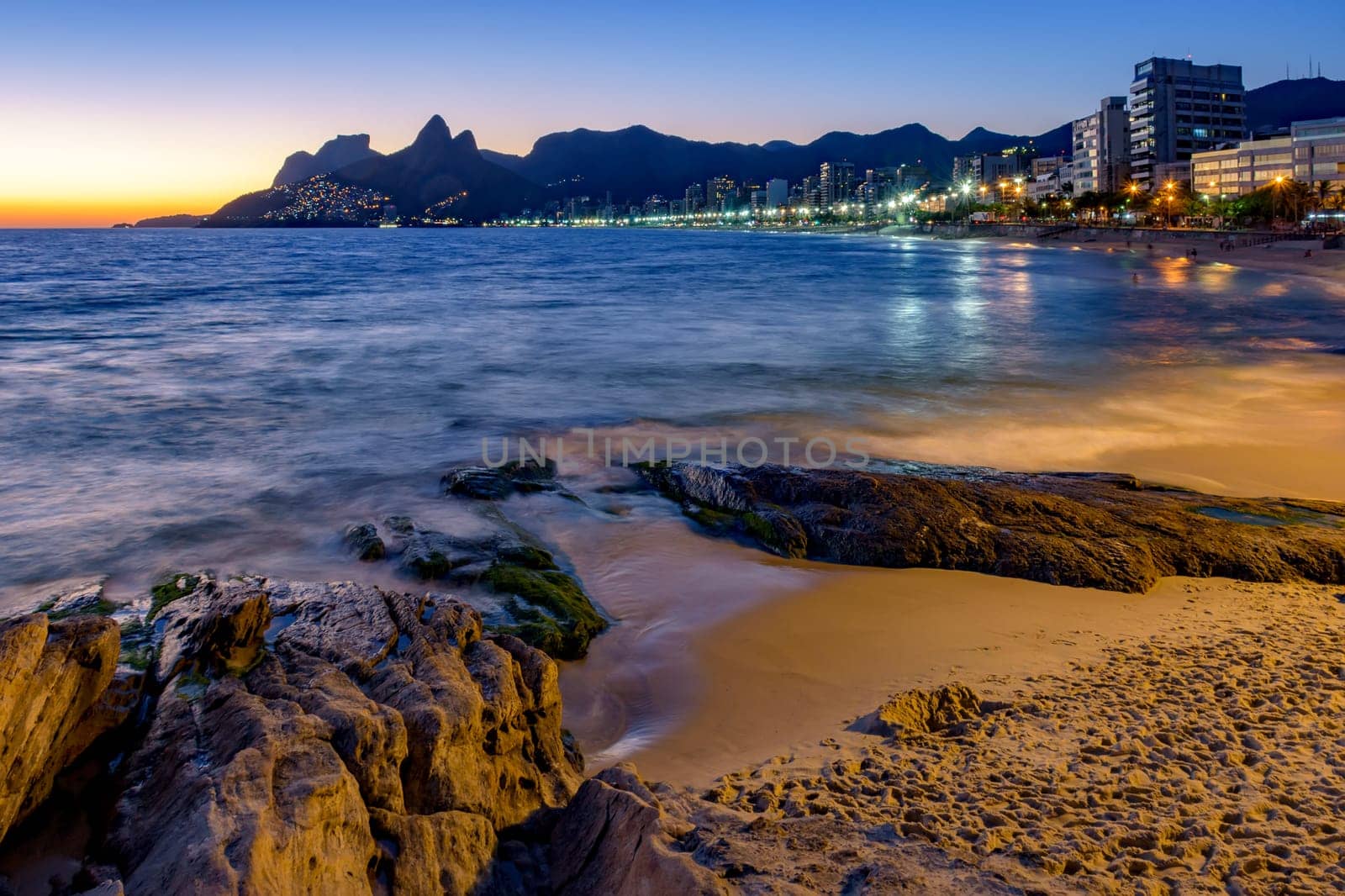 Ipanema beach with beautiful skyline and sunset. City lights and buildins araoud the ocean