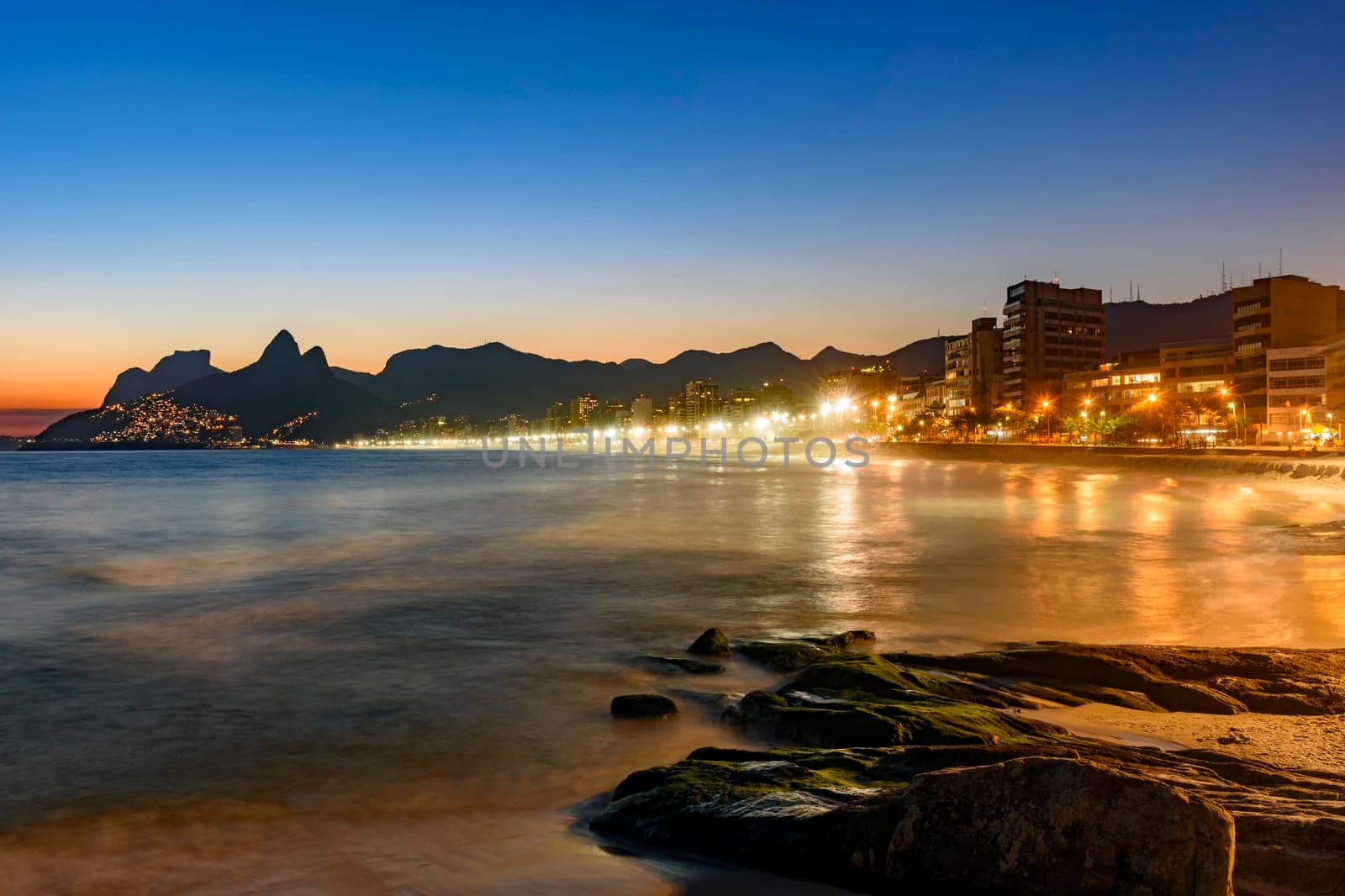 Ipanema beach with beautiful skyline and sunset. City lights and buildins araoud the ocean