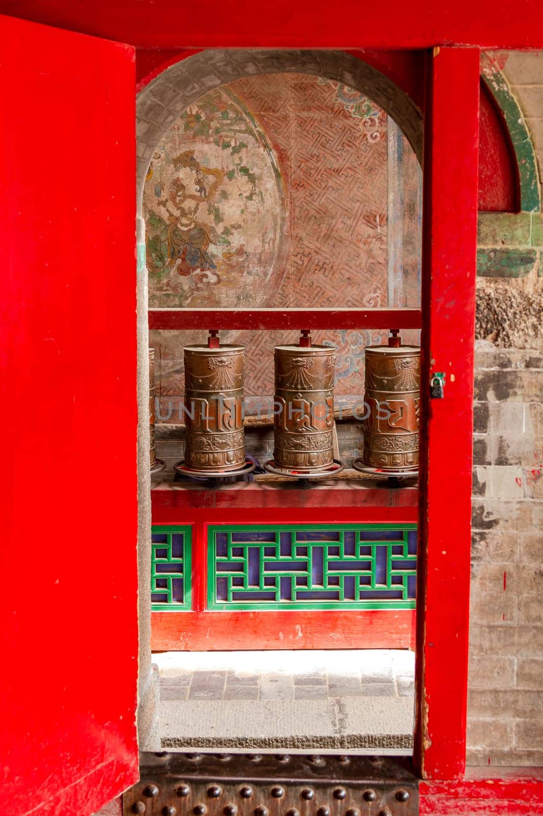 Prayer wheels behind a gate in a Tibetan temple of the Kumbum Jampaling monastery complex in Xining, China, Asia