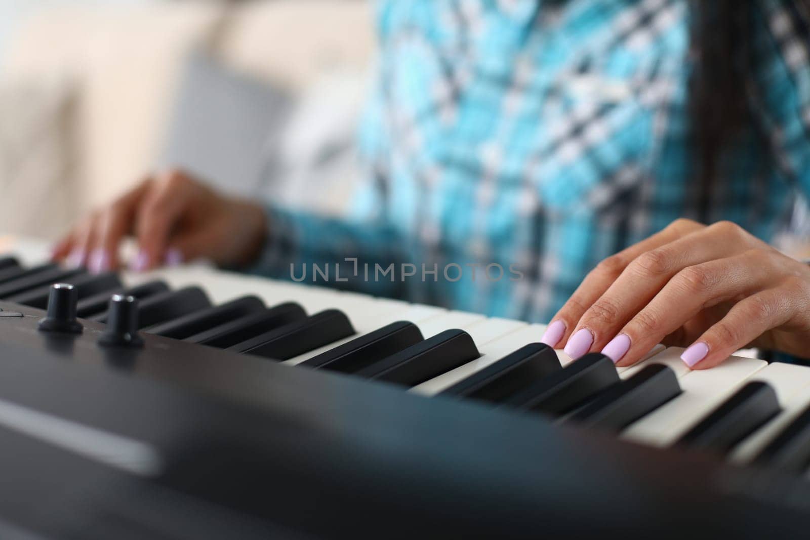 Woman hands playing electric piano at home performing musical composition closeup by kuprevich