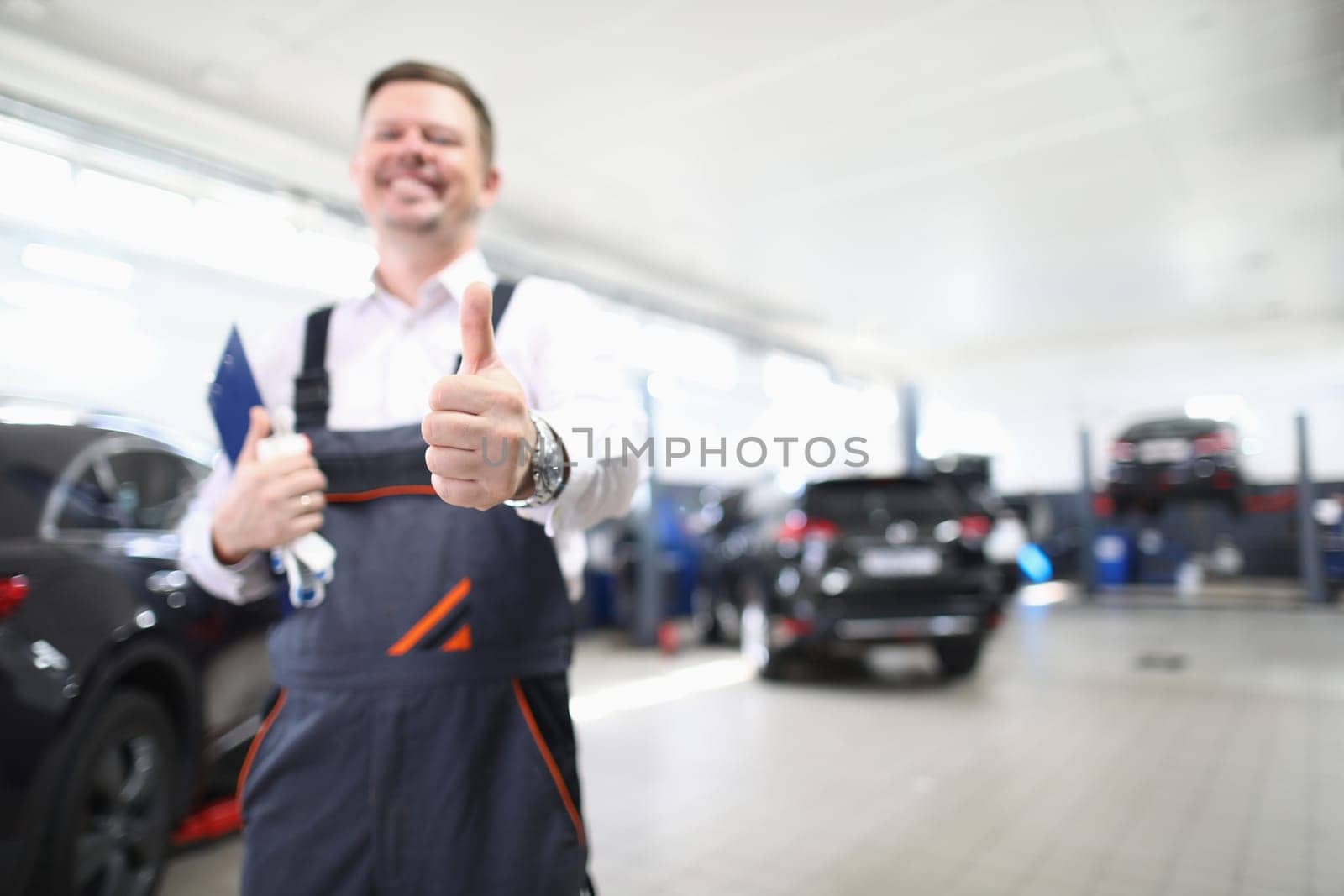 Master repairman holding clipboard with documents and showing thumb to auto repair shop by kuprevich