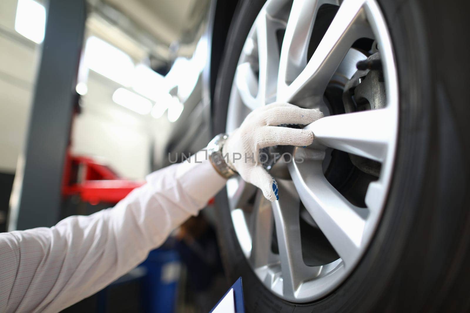 Mechanic changes car wheel in auto repair shop by kuprevich