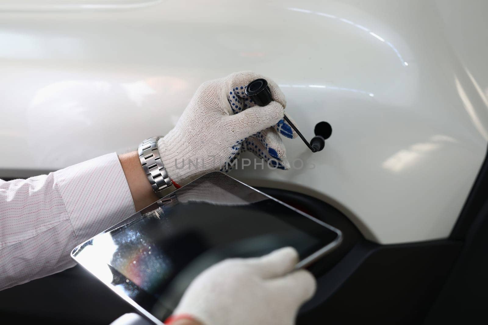 Auto mechanic holds tablet and car tube on white auto. Applications for car diagnostics and electronics