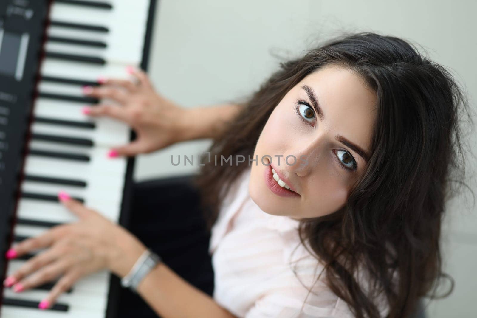Portrait of happy woman looking up and playing synthesizer. Beautiful woman at music lesson concept