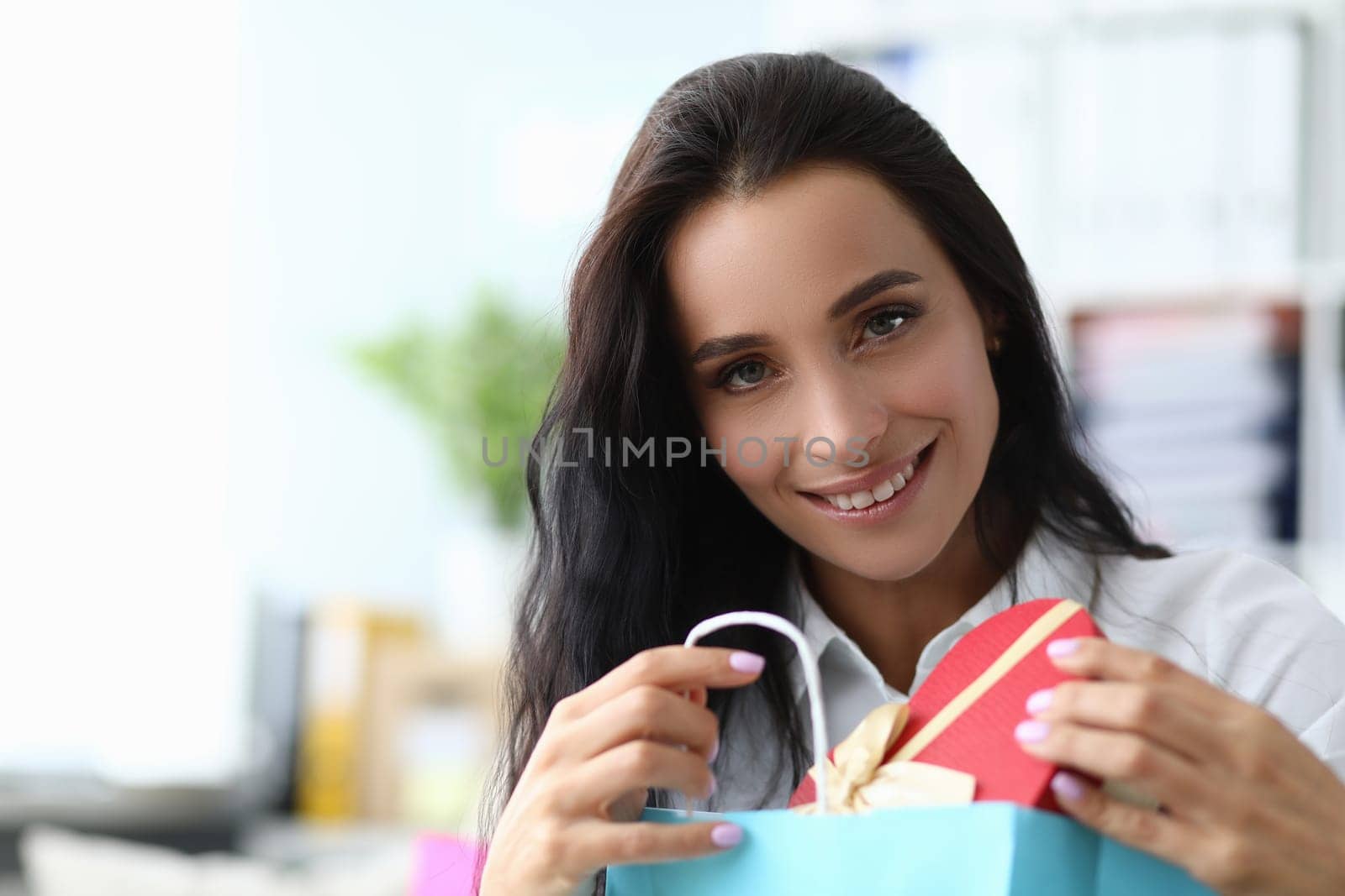 Smiling beautiful woman takes out gift from package. Surprises and gifts for woman concept