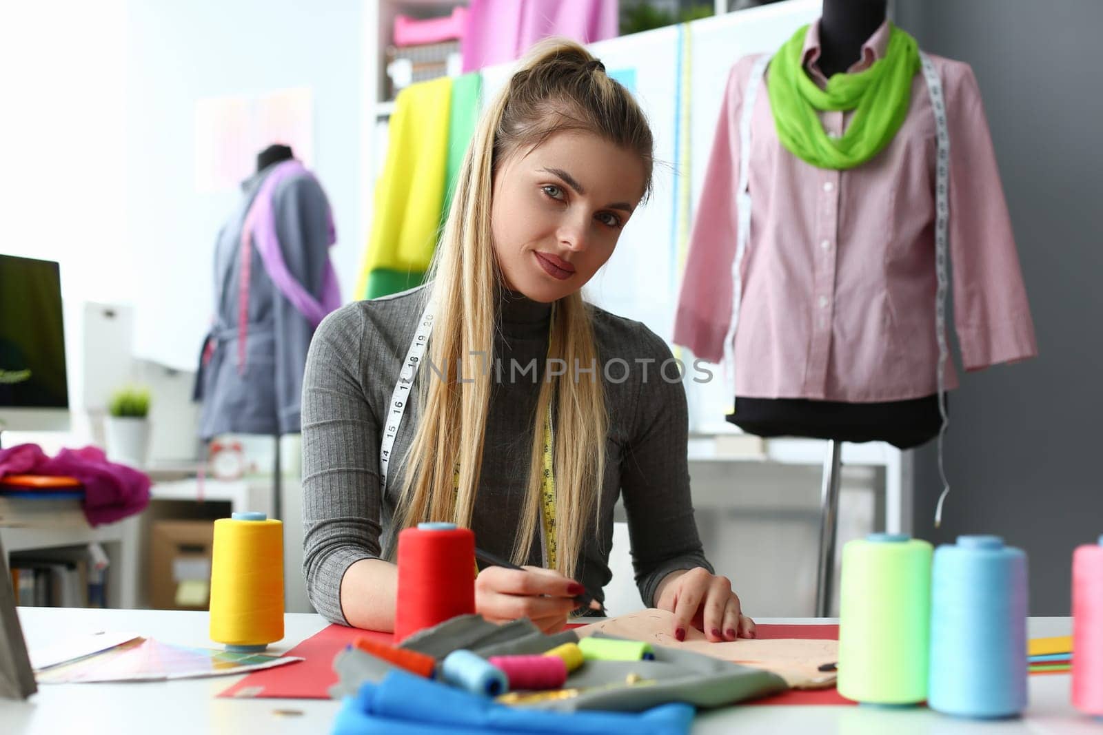 Young female fashion designer creating new fashionable clothes. Atelier and tailoring concept