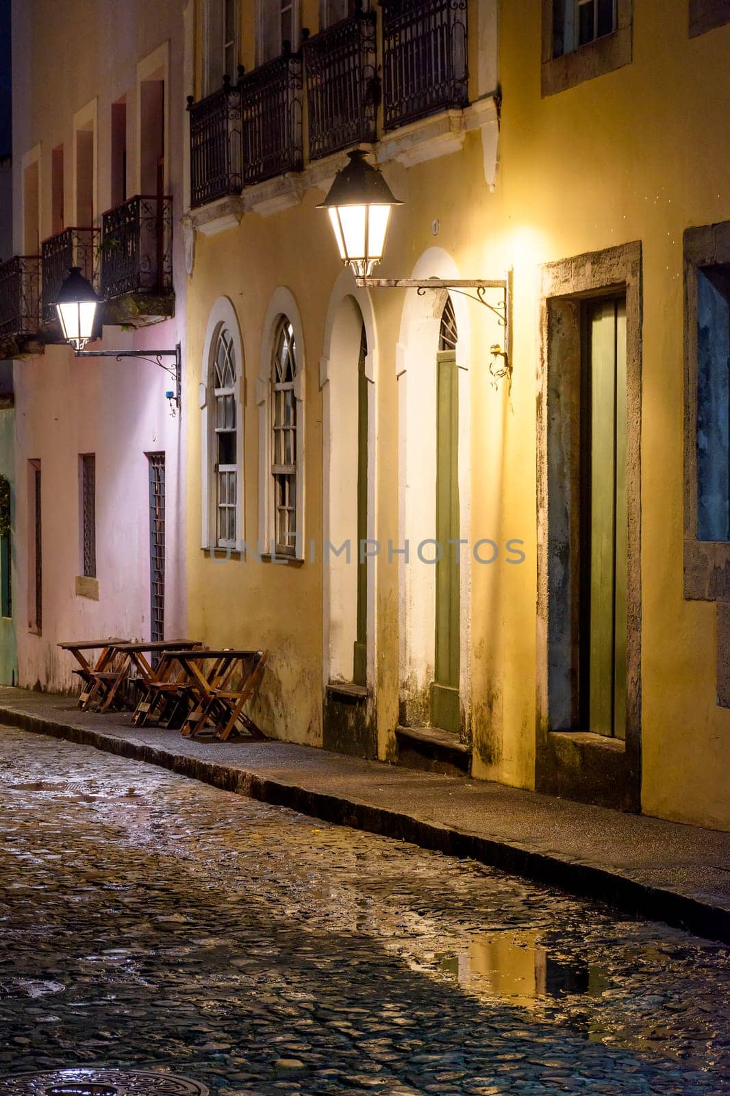 Old cobblestone street with lantern-lit colonial houses at night in the Pelourinho neighborhood of Salvador, Bahia