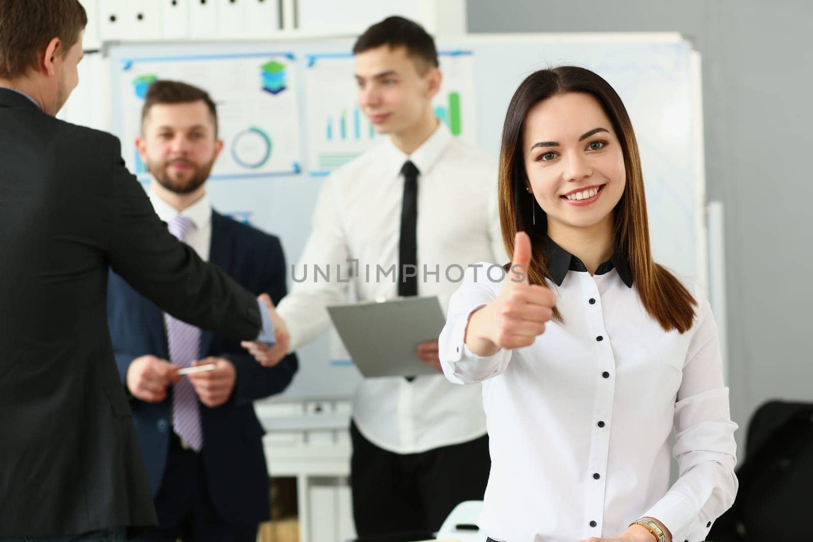 Happy businesswoman feels confident in team and holds thumbs up. Successful business team concept