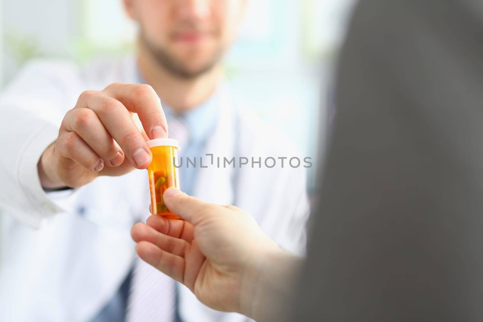 Doctor gives male patient jar of medical pills by kuprevich