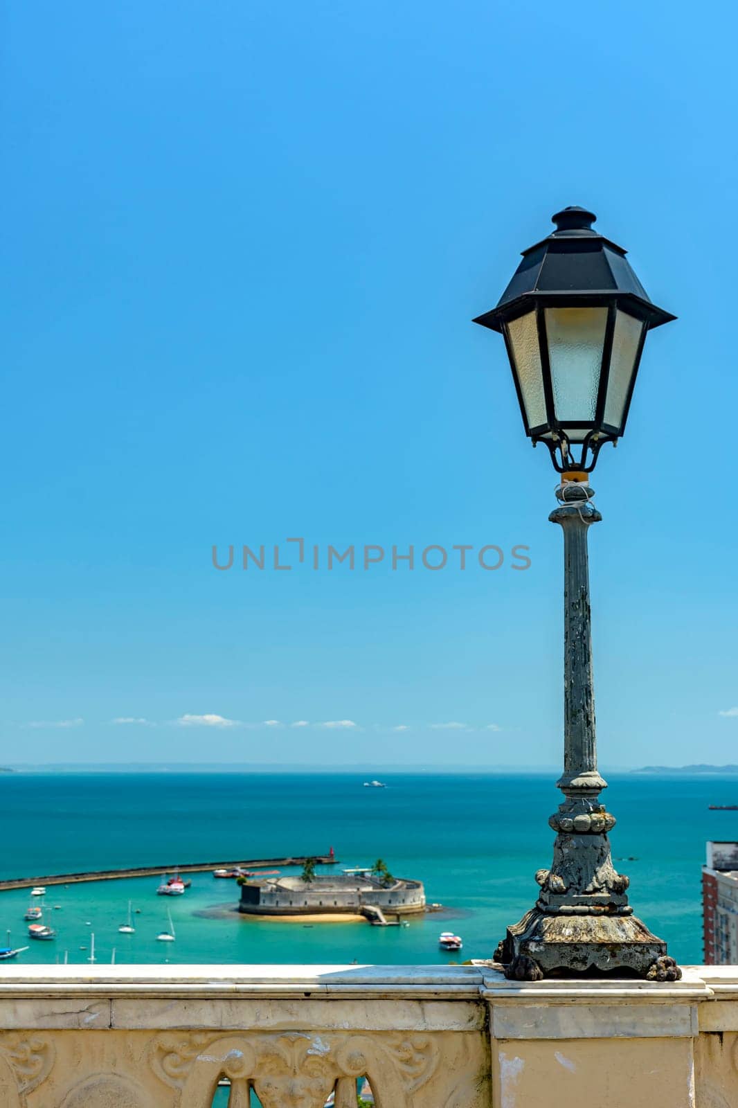 Old lamppost on a wall overlooking the sea and historic fortification in Todos os Santos Bay in Salvador, Bahia Todos os Santos Bay in Salvador, Bahia