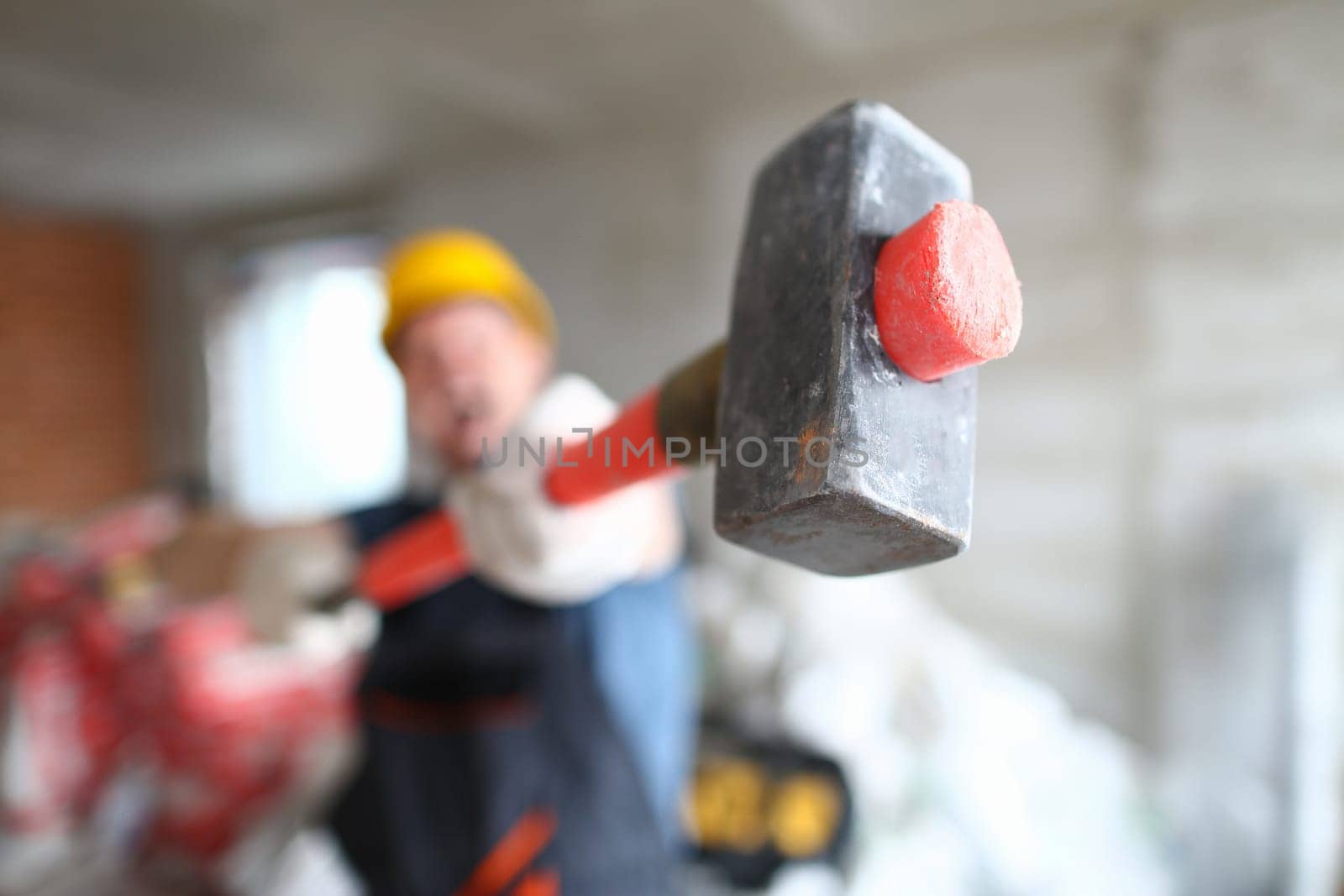Builder holding a construction hammer at construction site closeup by kuprevich
