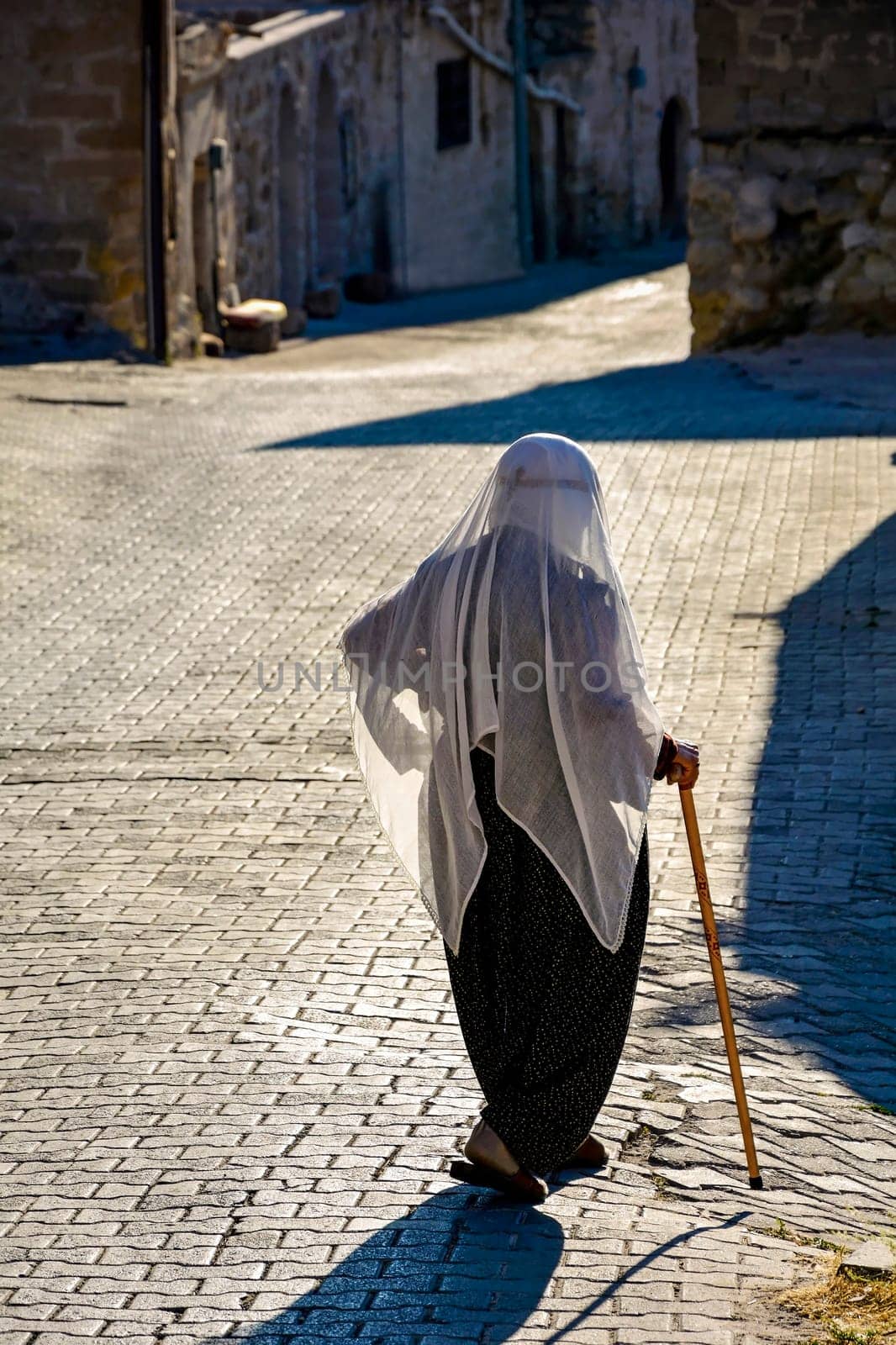 Old lady wearing the clothes and Islam veil walking the streets of Goreme in Cappadocia, Turkey