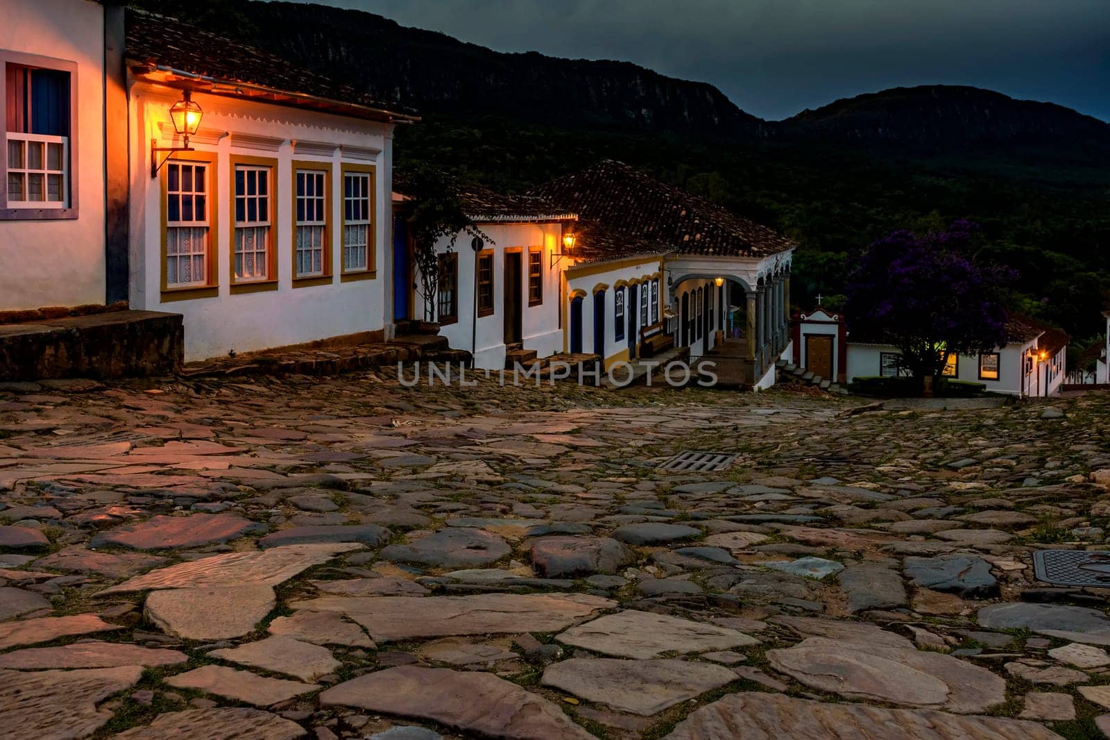 Streets and houses of the historic  city of Tiradentes illuminated at dusk with the mountains in the background