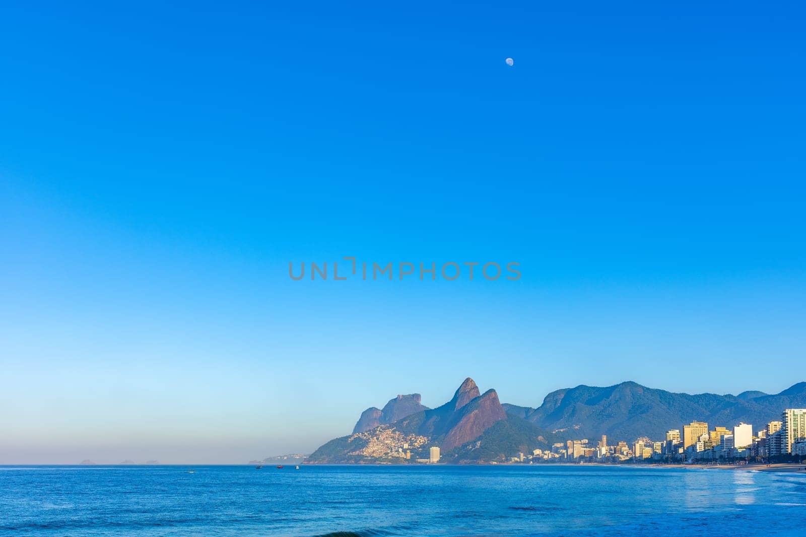 Sunrise on Ipanema beach in Rio de Janeiro with the moon in the sky