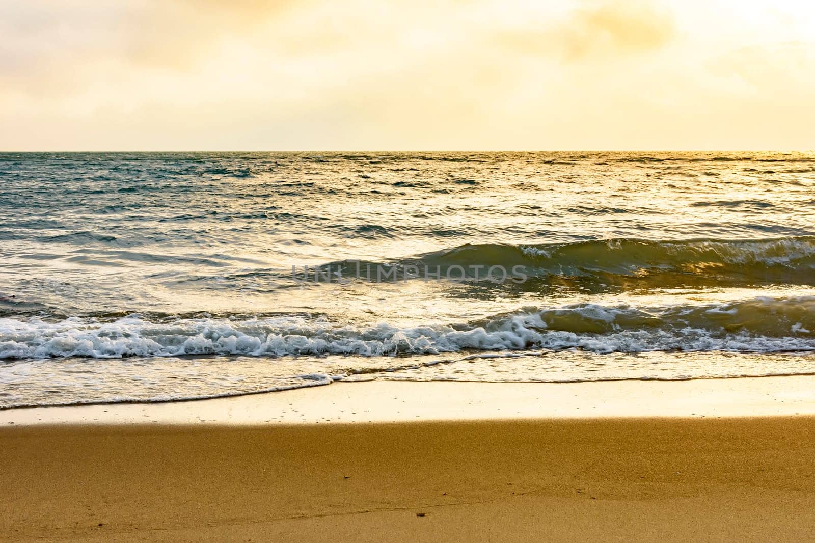 Sunset at the sea of Ilhabela island in Sao Paulo litoral with the beach, waves, ocean and the horizon during the summer