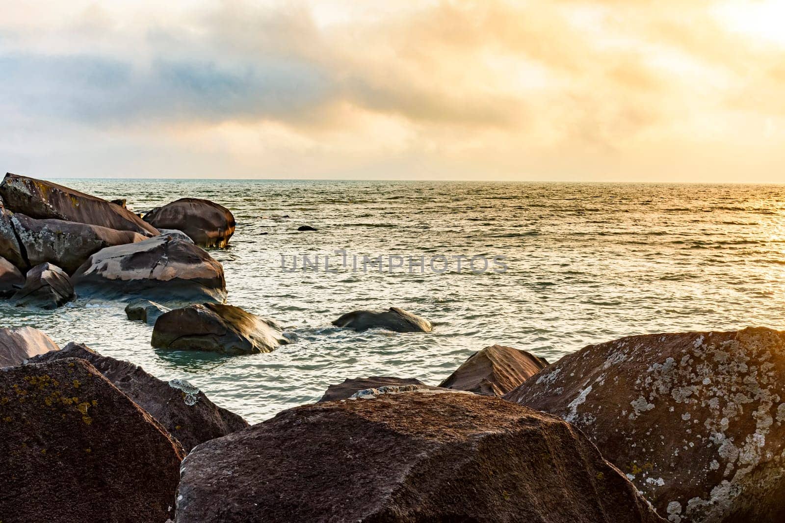 Sunset at the sea of Ilhabela island with the ocean, horizon and stones during the summer