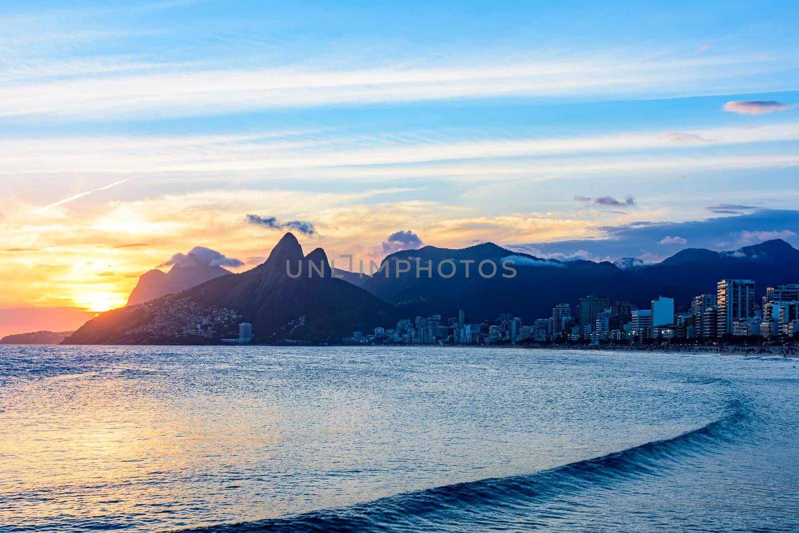 Sunset behind the mountains of the city of Rio de Janeiro on Ipanema beach