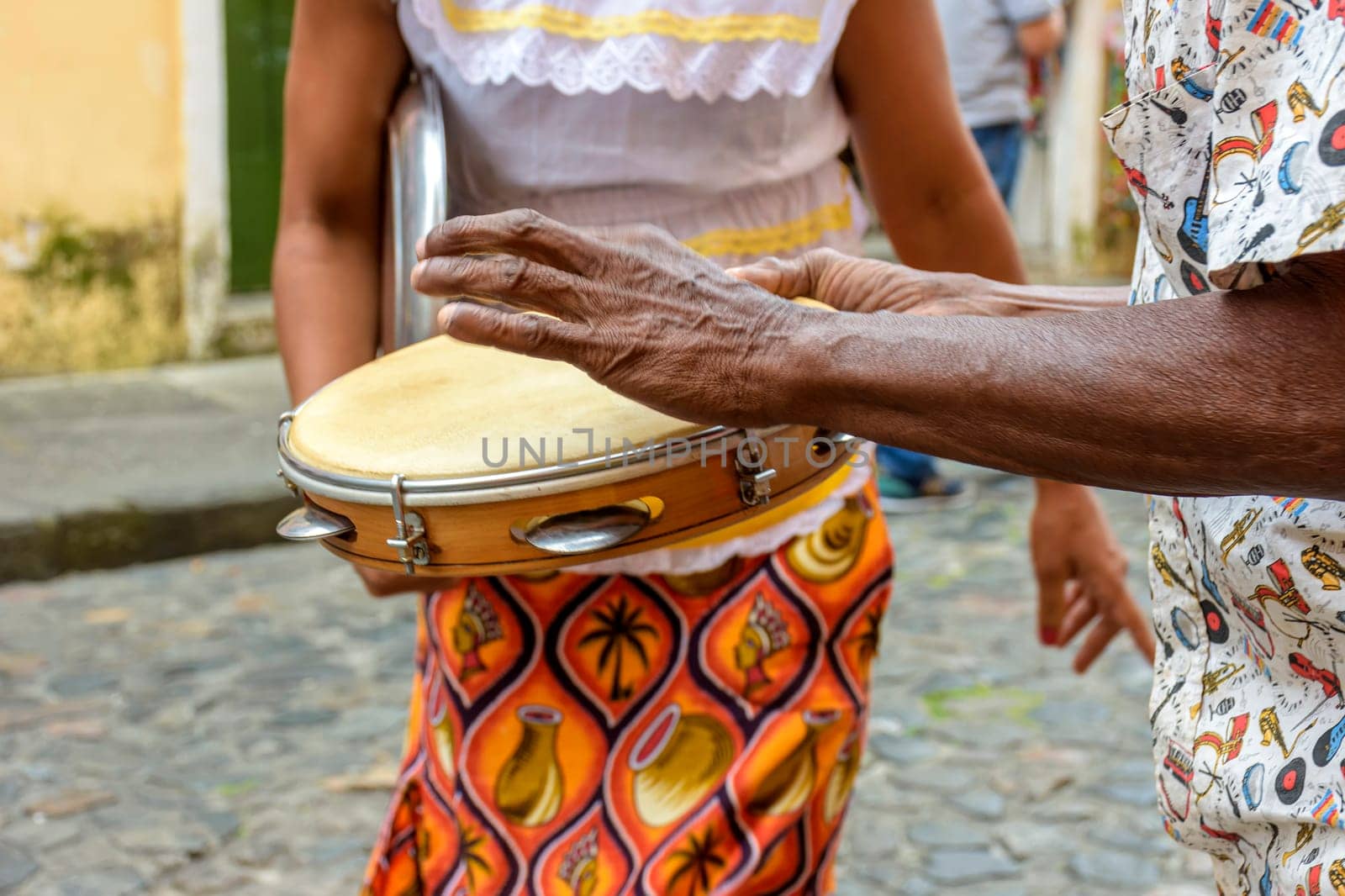 Tambourine player with a woman in typical clothes dancing in the background by Fred_Pinheiro