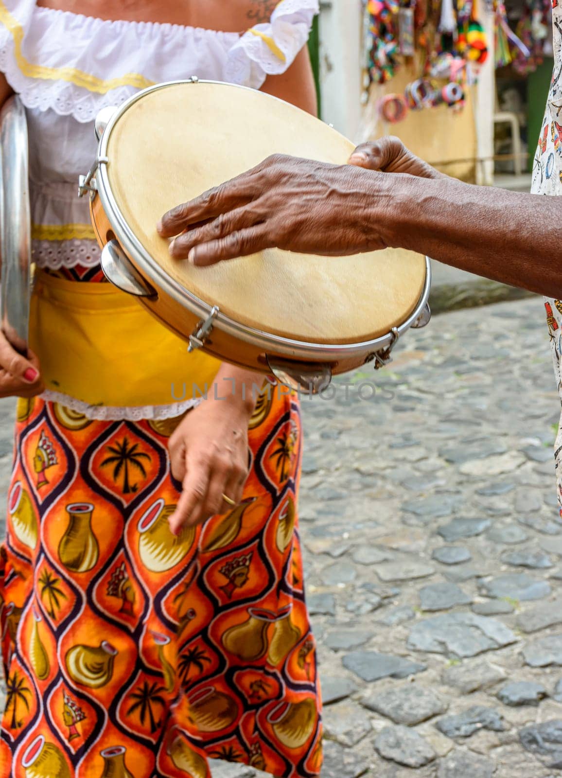 Tambourine player with a woman in typical clothes dancing in the background in the streets of the Pelourinho district in Salvador, Bahia