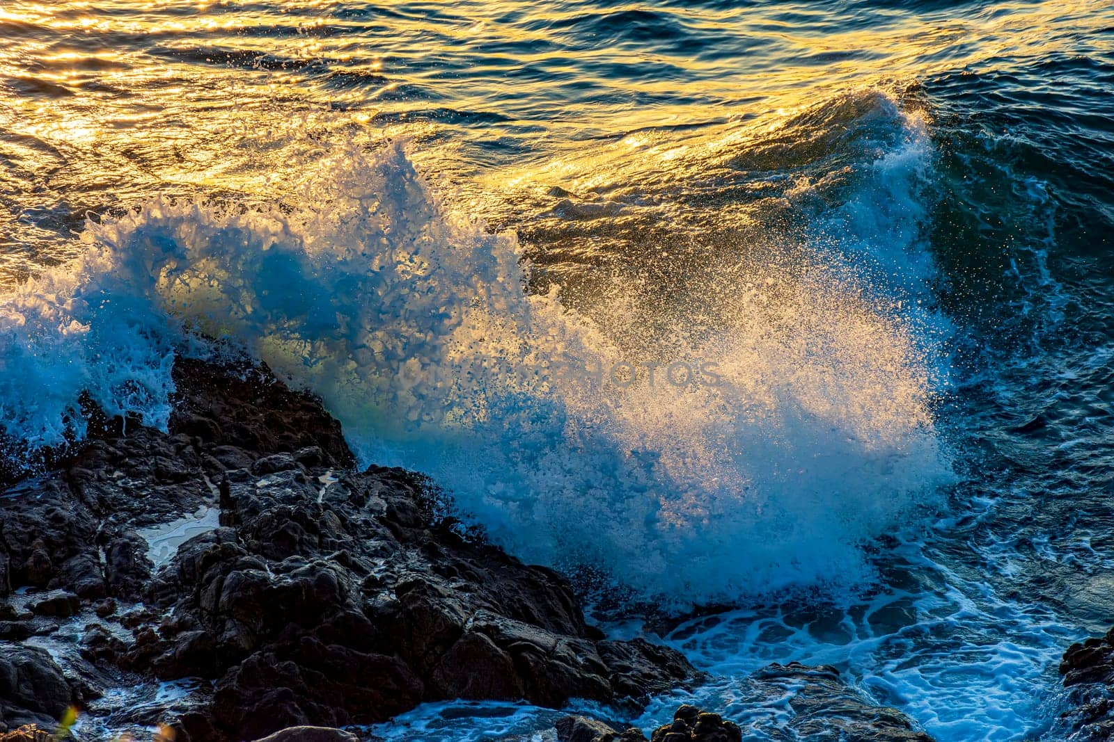 Water and sea foam splashing with the shock of waves against the rocks during sunset in the city of Salvador in Bahia