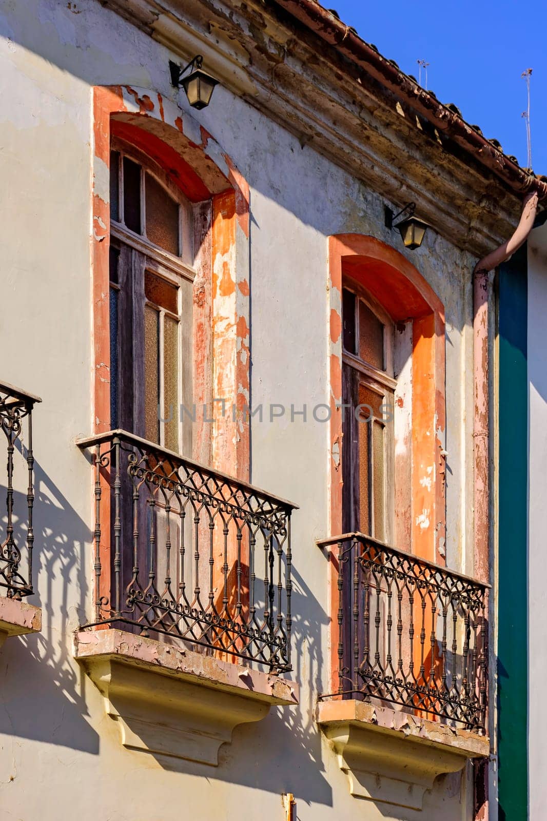 Window of old colonial style house with balcony and colorful frame with peeling paint in the ancient city of Ouro Preto in Minas Gerais, Brazil