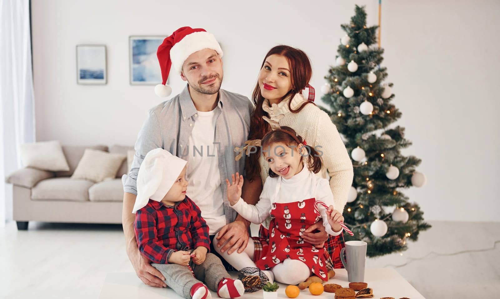 Sits against fir. Beautiful family celebrates New year and christmas indoors at home by Standret