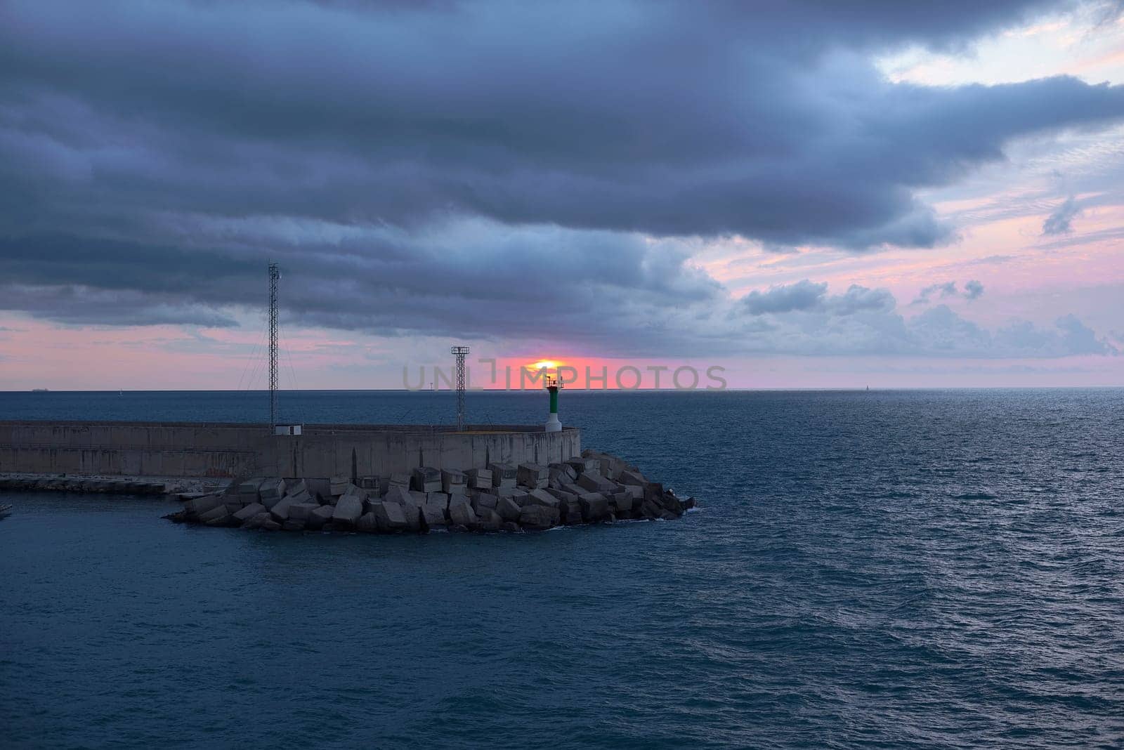 Sunrise from green lighthouse on maritime breakwater by raul_ruiz