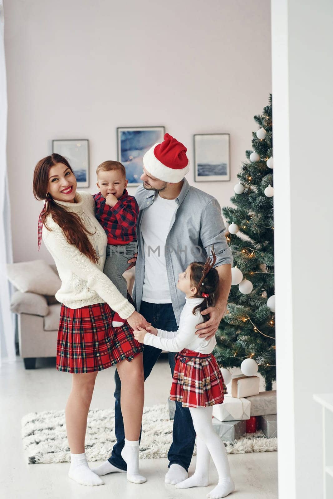 Standing together. Beautiful family celebrates New year and christmas indoors at home by Standret