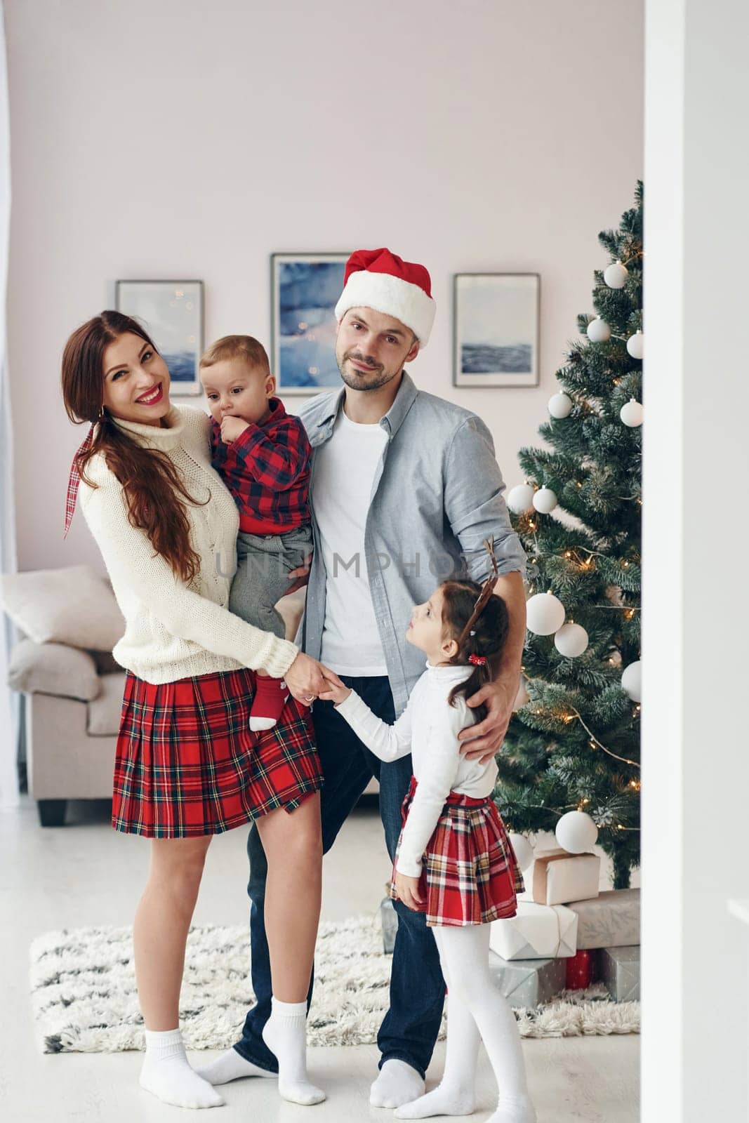 Standing together. Beautiful family celebrates New year and christmas indoors at home by Standret